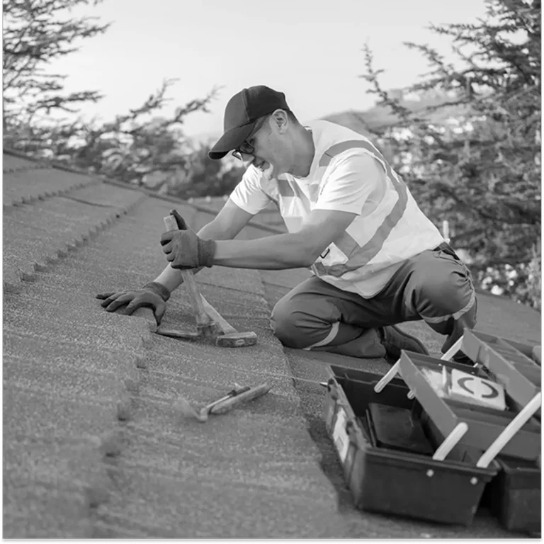Worker installing solar panels on a rooftop under clear sky.