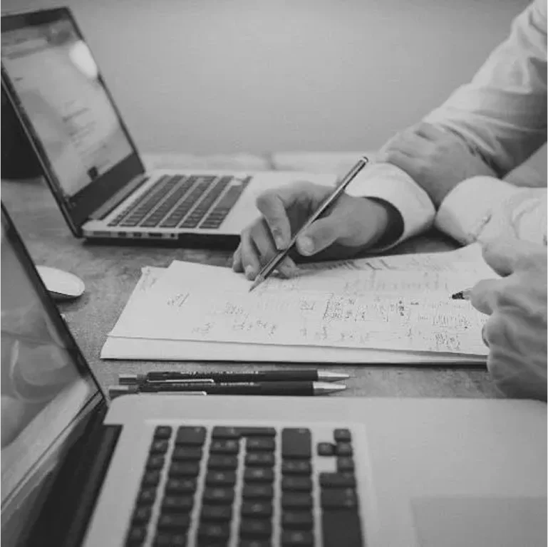 Two people collaborating with laptops and documents.