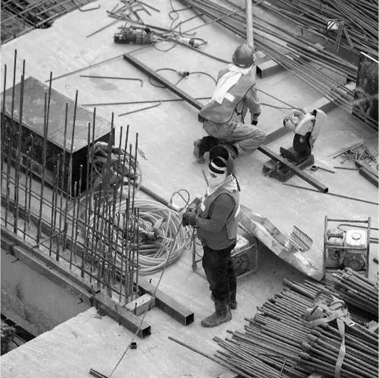 Construction workers working on a building site with steel reinforcements.