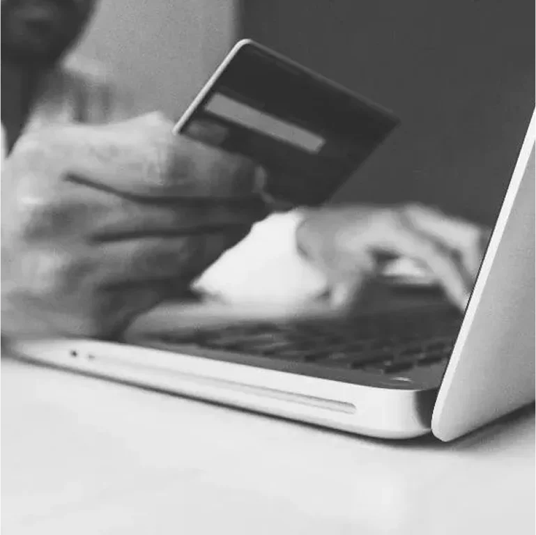 Person holding a credit card while using a laptop.