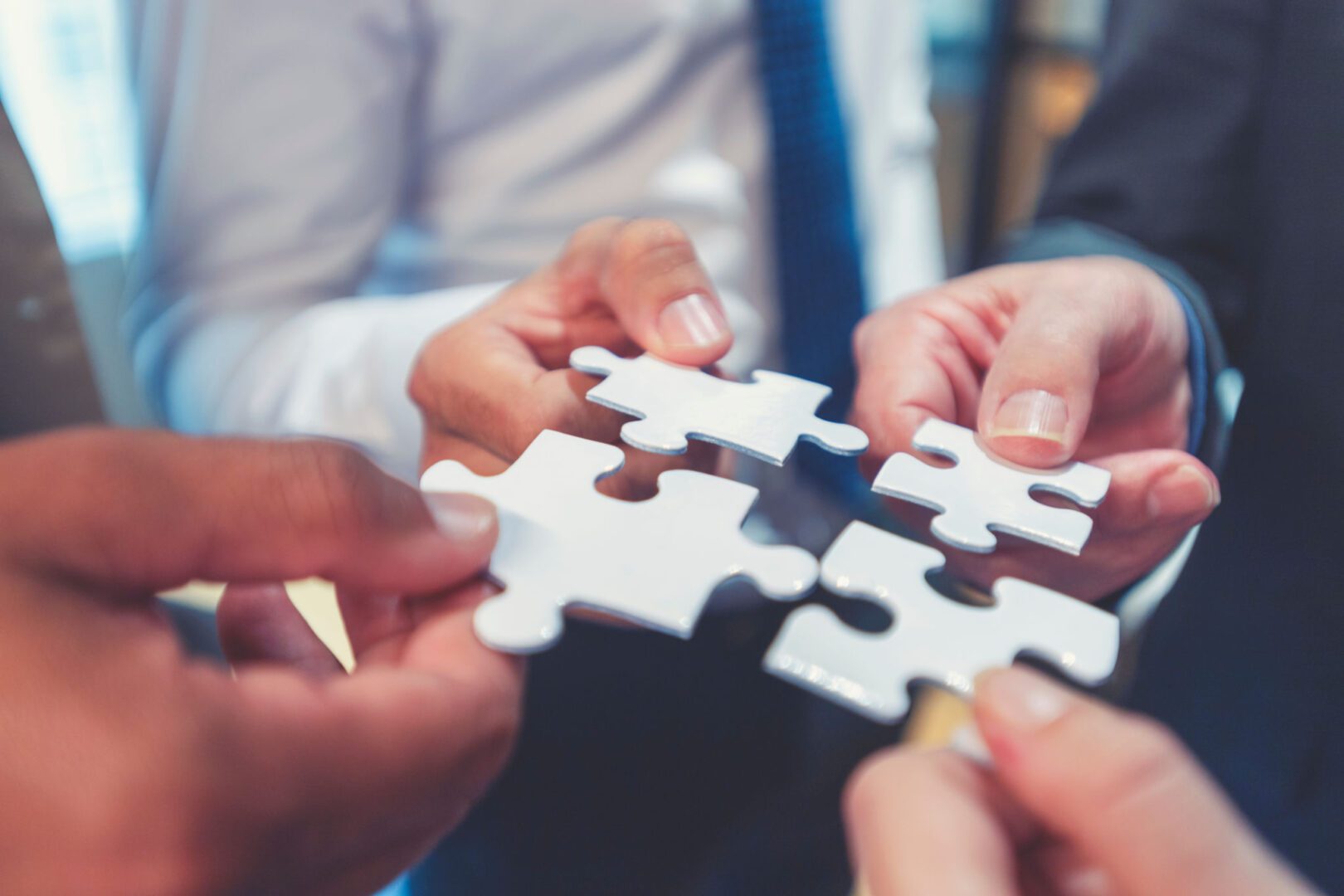 Hands holding puzzle pieces together in collaboration.