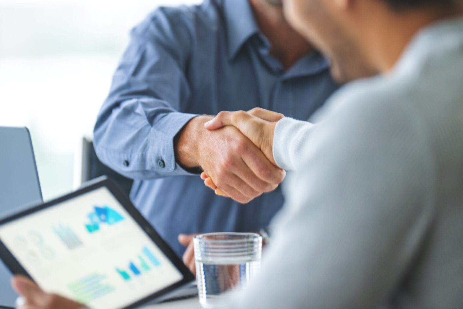 Two people shaking hands in meeting.