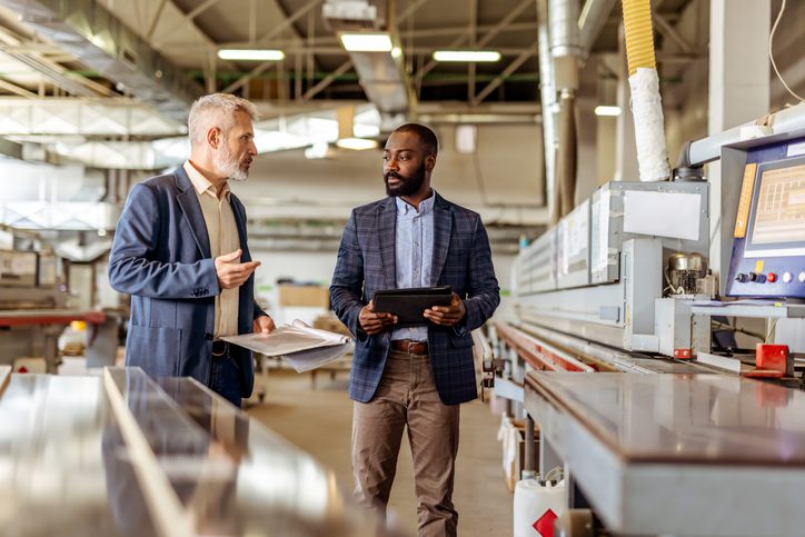 Two businessmen discussing work in an industrial setting.